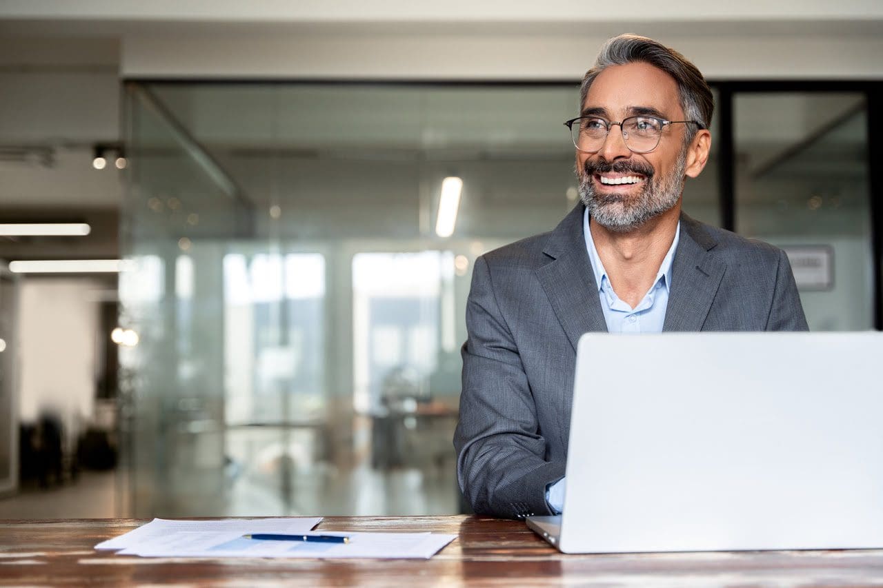 Smiling businessman working on laptop.