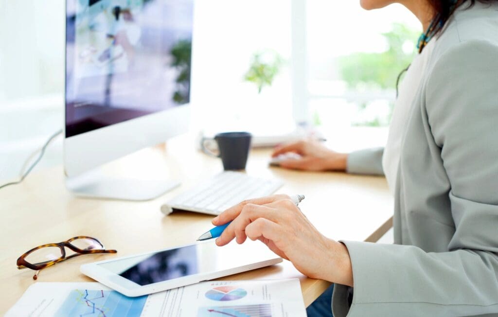 A consultant using an iPad while engaging with a small business owner or community group, reviewing financial documents collaboratively.