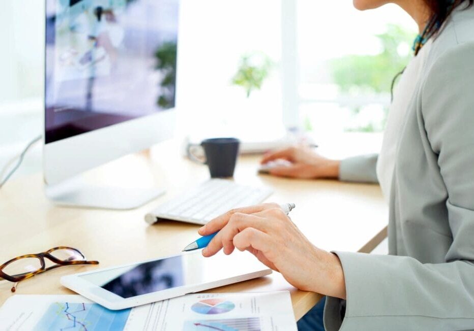 A consultant using an iPad while engaging with a small business owner or community group, reviewing financial documents collaboratively.